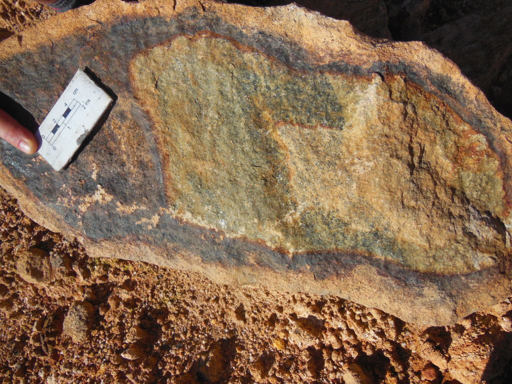 Weathered out boulder of lherzolite from gem quality olivine + pyroxene in core to serpentinite to lateritic mud outside.