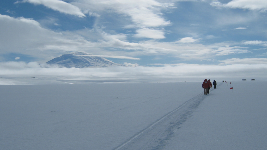 Figure 3.  Happy Camper participants follow the flag-marked route to the training hut. Mt. Eribus looms in the background.