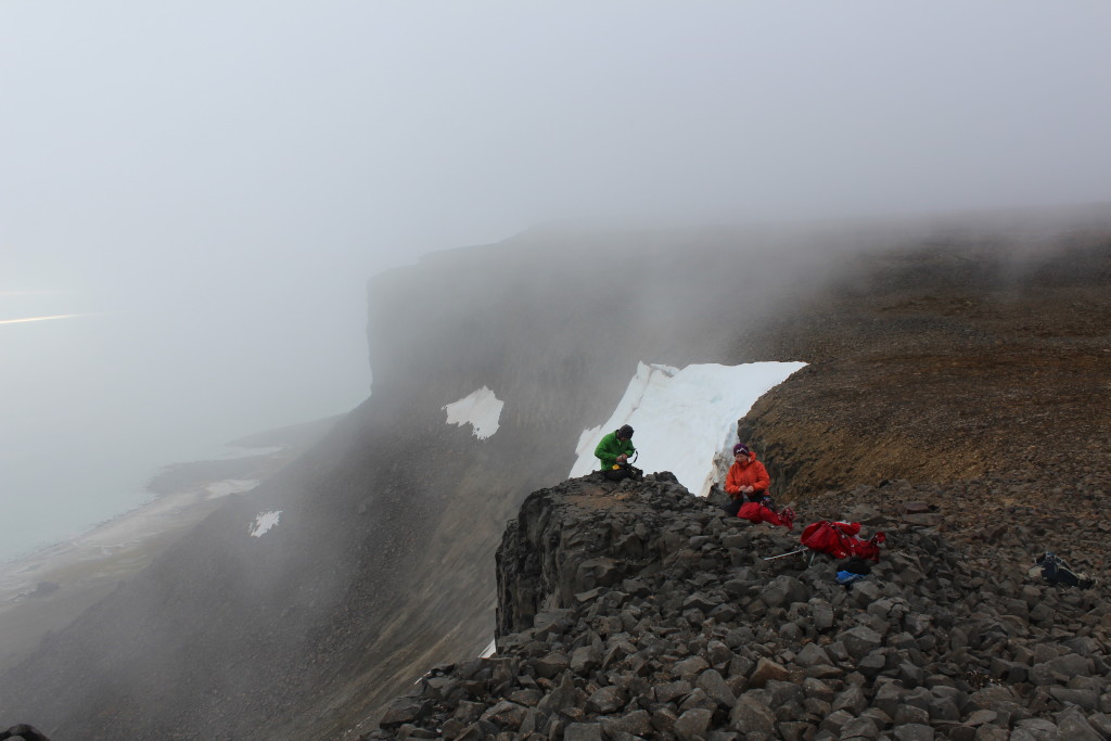 Measuring orientation of striations and collecting a cosmogenic exposure dating sample from a polished basaltic bedrock on the edge of a 300m high cliff ledge.