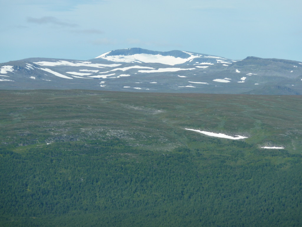 Fig. 4: View to west onto the Ammarfjället, essentially constituted by rocks of the Seve Nappe Complex, with the remote, 1611 m high Rerrogaisse mountain massiv and its characteristic relic kettle glacier. The foreground shows the western flank of the Vindelälven valley exposing metagreywackes of the Ammarnäs Nappe Complex.