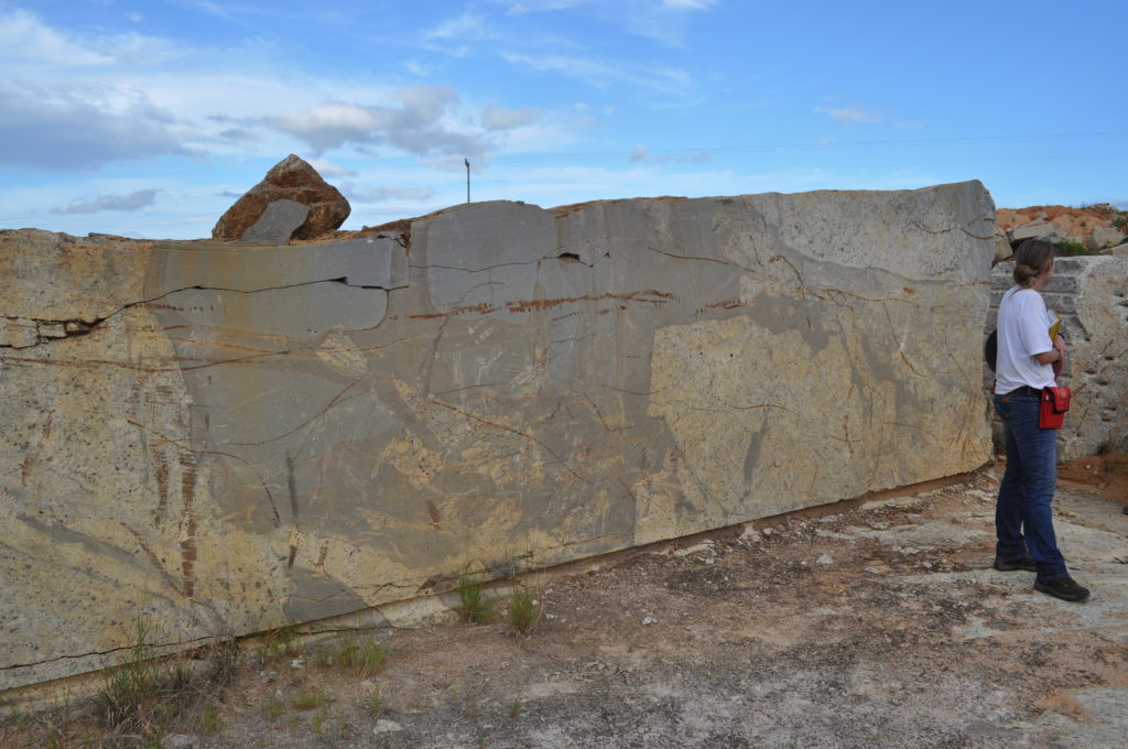 Figure 6 –One of the many remaining blocks of granitoids that were left behing after the mining in this location ended. Interestingly, many of these granitoids bear metasedimentary xenoliths. This is me in my first field trip, as an undergraduate student, having no idea what that meant.