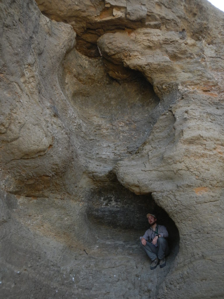 Matthew Nikitczuk sits inside a windblown cavity on the face of a tuff outcrop in the Black Hills. Photo by Nevena Novakovic.