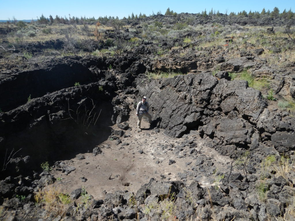 Matthew Nikitczuk standing in the middle of a lava field during a trek to collect samples from a cinder cone at its center. Photo by Frank Popoli.