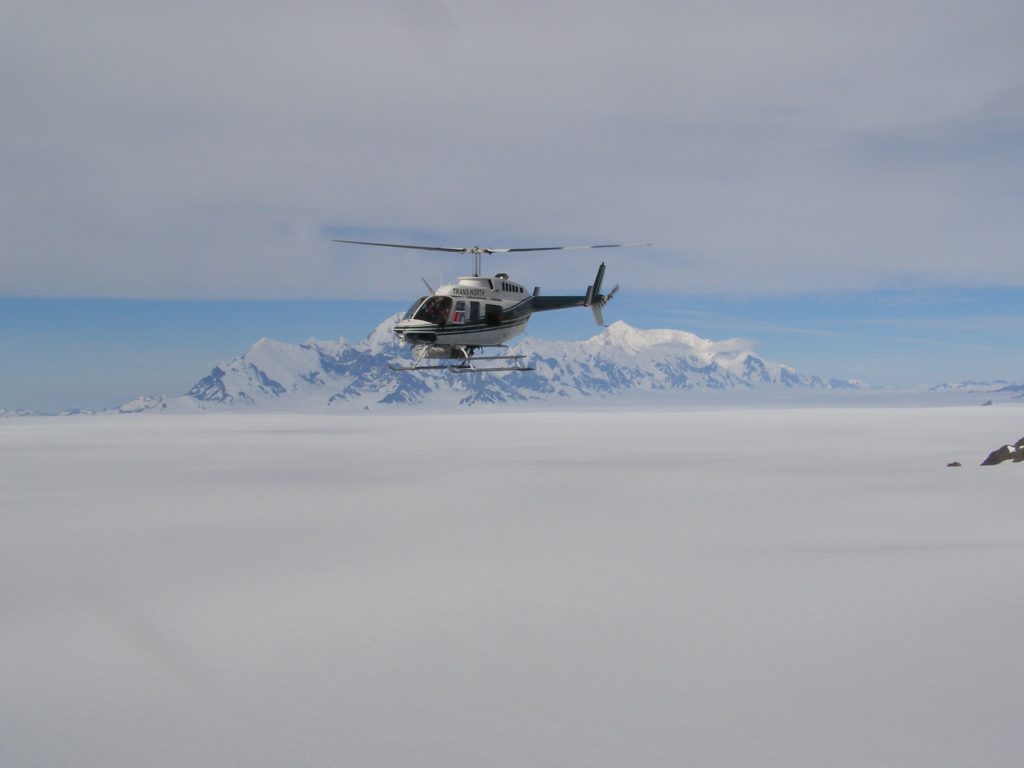 Helicopter flying above Seward Icefield in front of Mount St. Elias in the southwest.