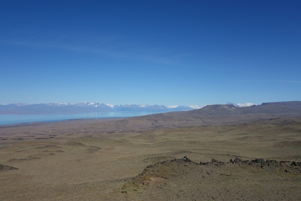 Basalt plateaus and dikes in the foreground; the Andes with its plutonic units in the background (and reflected in the glacial lake).